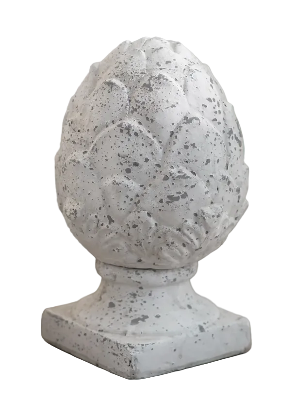 A decorative white faux-stone pinecone garden ornament with a textured, speckled finish, displayed on a wooden surface with a blurred background.