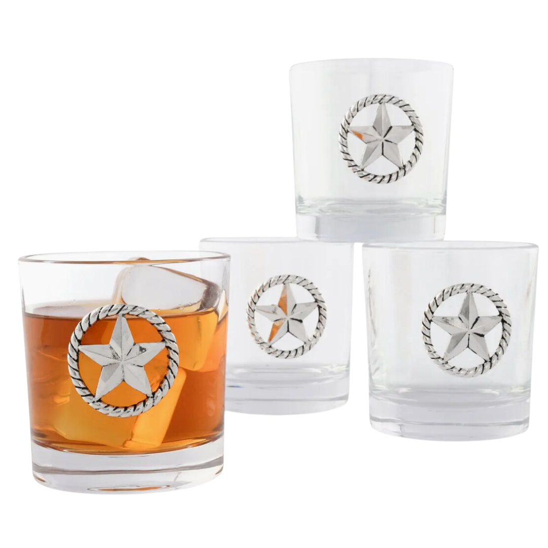 A set of four clear bar glasses, each with a unique metal Western star accent on the side, filled with a brown liquid, presumably a beverage.