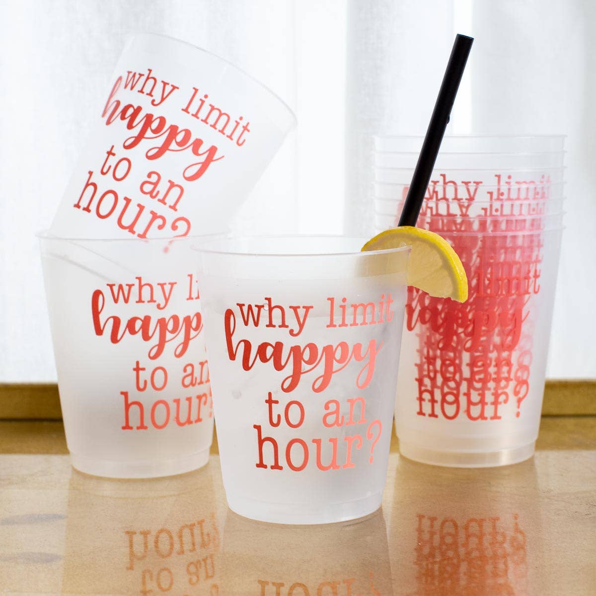 Clear plastic cups with red text and a lemon wedge on a wooden surface