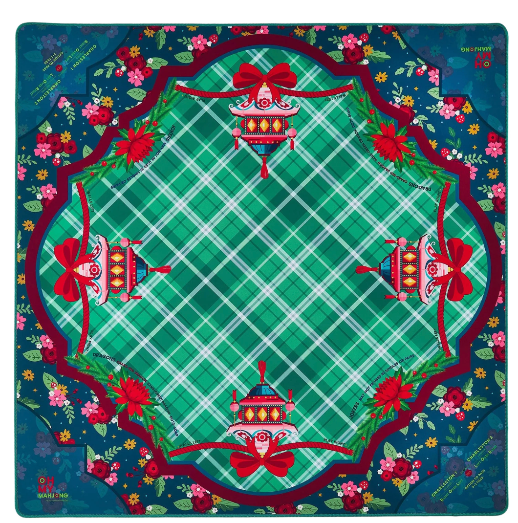 A Mahjong mat featuring a festive Christmas design with a green plaid center, red bows, poinsettias, and ornate holiday ornaments, surrounded by a dark blue floral border.