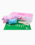Mahjong set with pink box, green mat, dice, and tiles on a white background