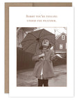 Vintage-style card with a black and white photo of a child holding an umbrella, accompanied by the text 'Sorry you're feeling under the weather.'.