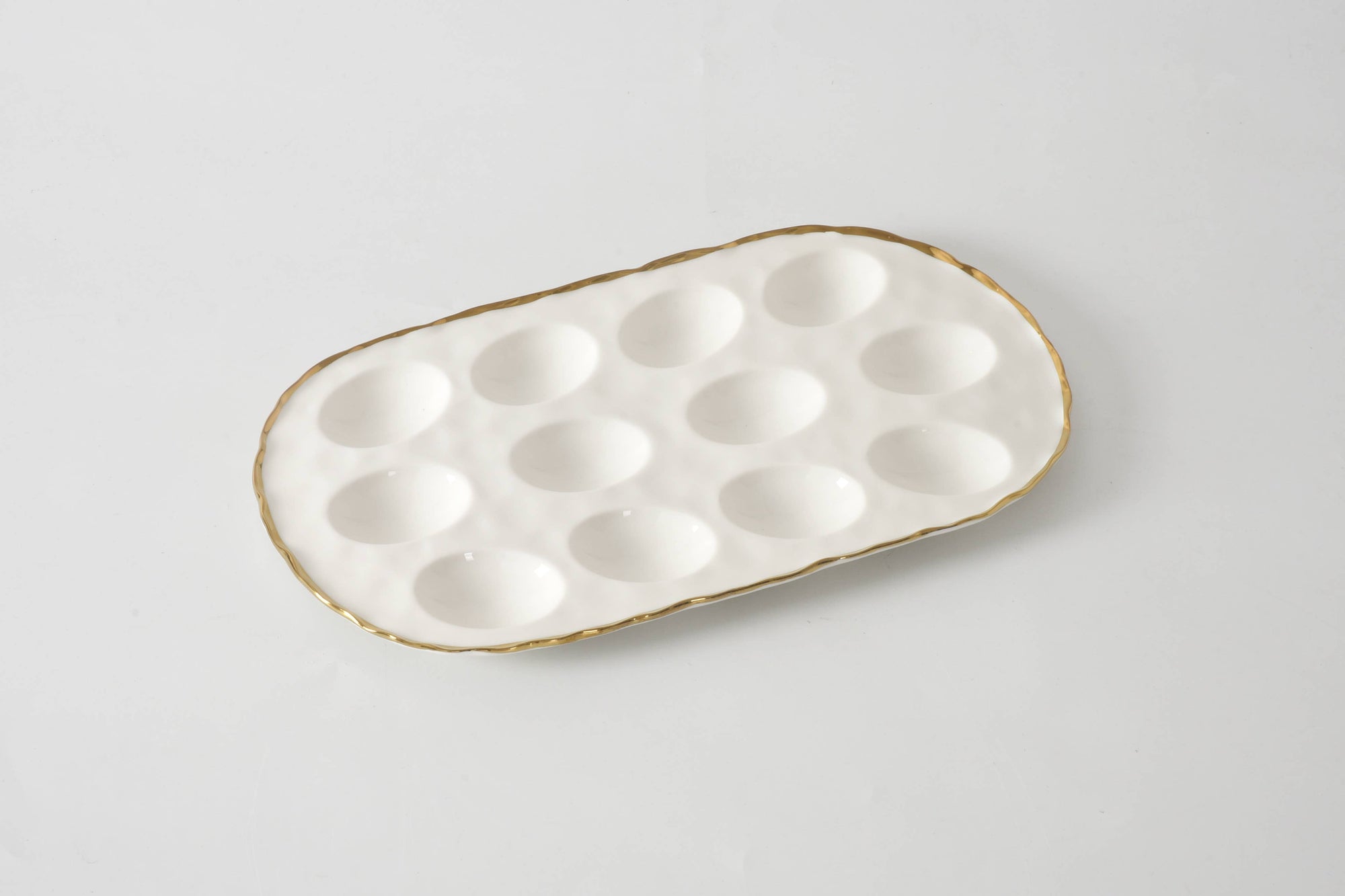 White ceramic egg tray with gold rim on a light gray background