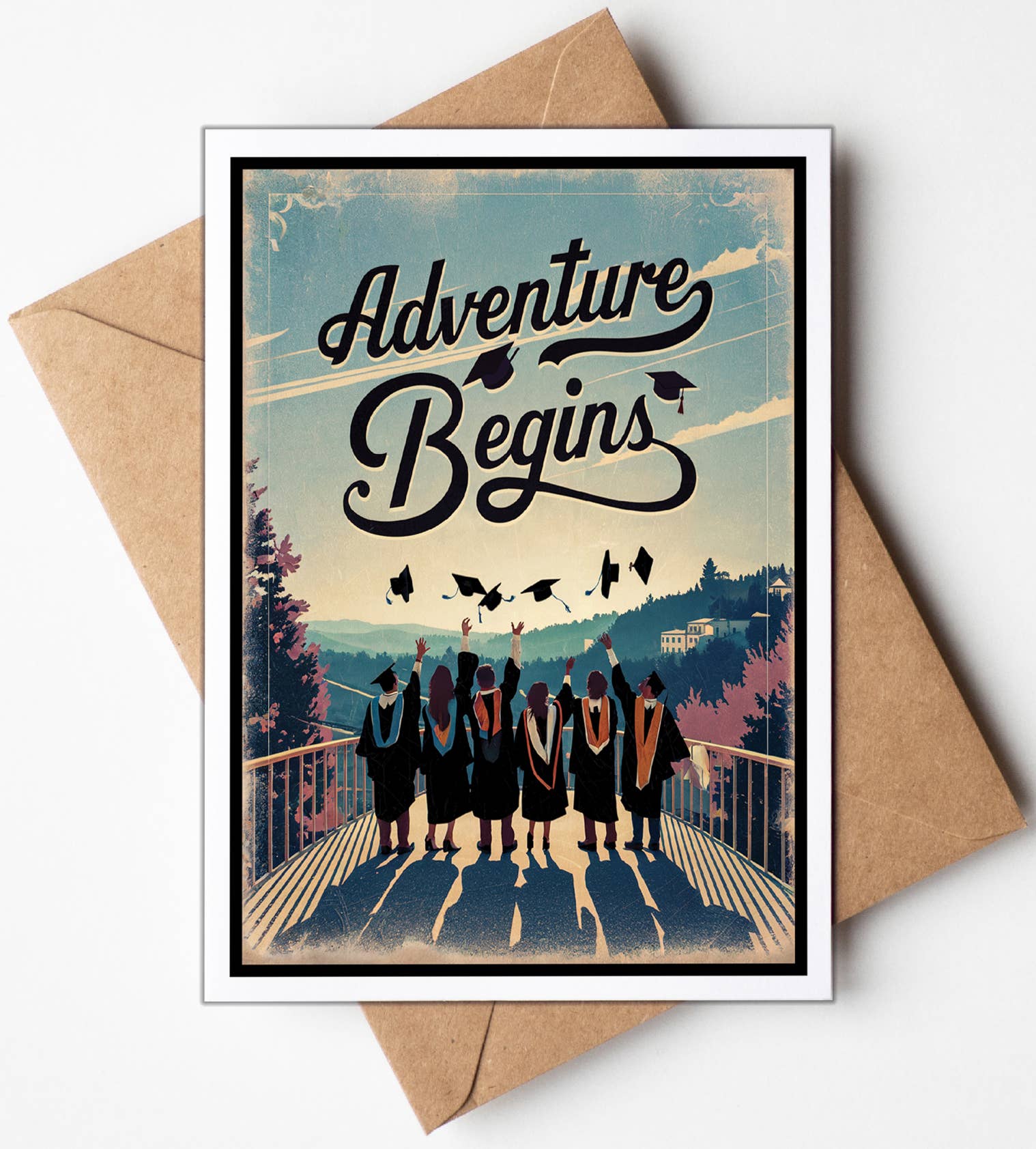 Greeting card with graduates and 'Adventure Begins' text on a scenic background, placed on a brown envelope.