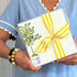 A person holding a clear cellophane bag with a lemon tree design and a yellow ribbon.