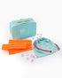 Teal game box with orange sticks, pink cards, and a drawstring bag on a white background