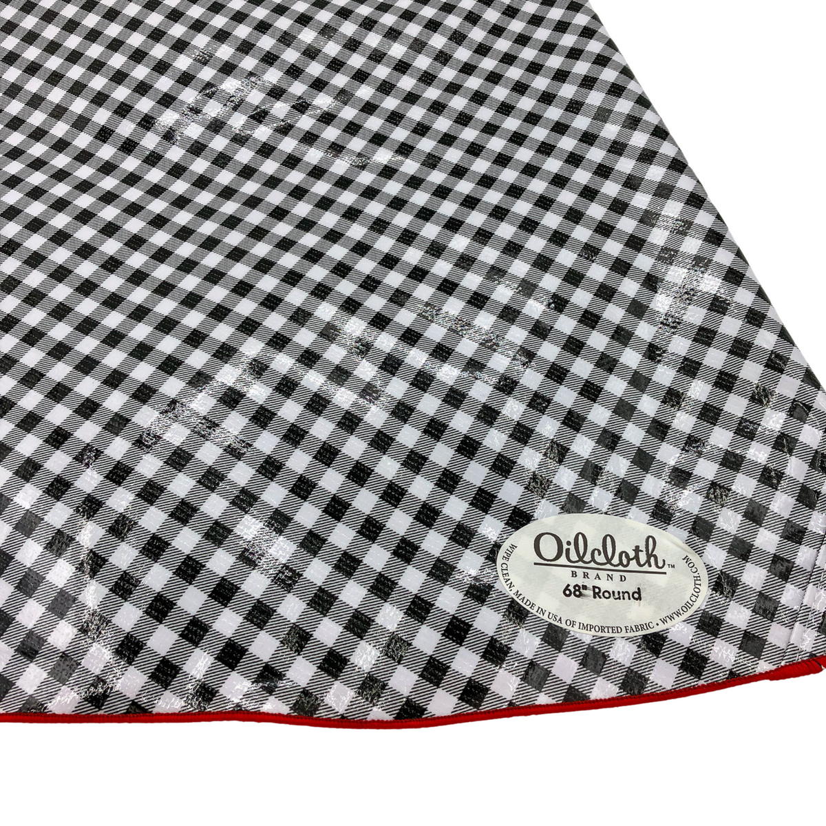 A black and white checkered round tablecloth with a red trim on the edge, displaying the brand name 'Oilcloth' with a label indicating '60" Round'.
